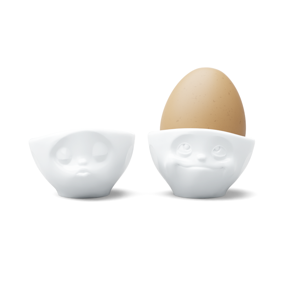 Set of two egg cups in white from the porcelain product family of fun dishware by FIFTYEIGHT Products. Set features two egg cups in white, featuring 'kissing' and 'dreamy' facial expressions. Dishwasher and microwave safe bowls. Shipped in exclusively designed gift box.