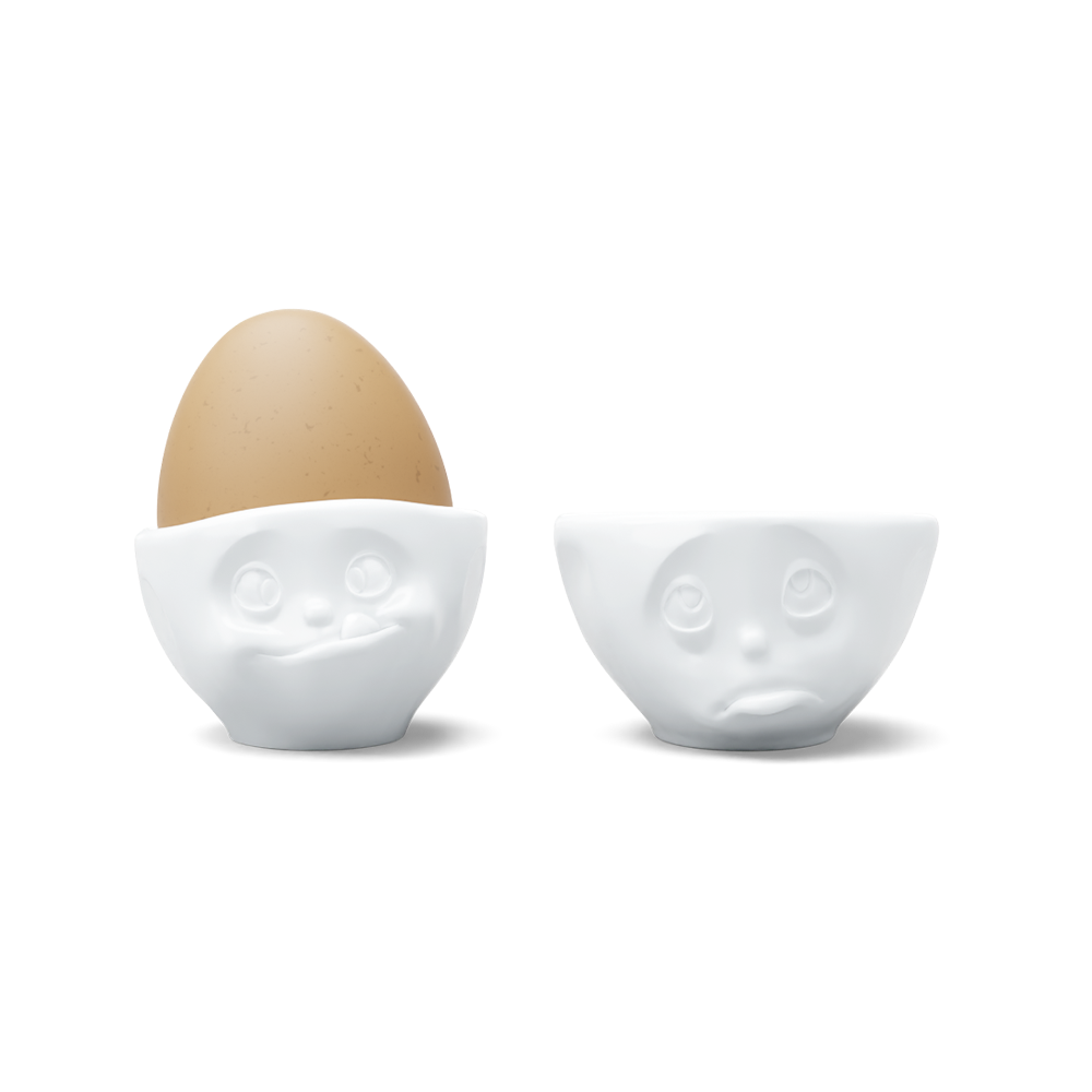 Set of two egg cups in white from the porcelain product family of fun dishware by FIFTYEIGHT Products. Set features two egg cups in white, featuring 'Oh please' and 'tasty' facial expressions. Dishwasher and microwave safe bowls. Shipped in exclusively designed gift box.