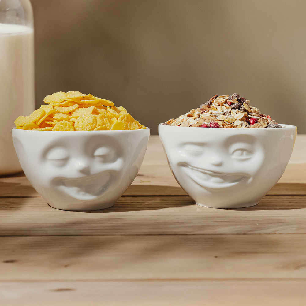 Set of two 6.5 oz. bowls in white from the porcelain product family of fun dishware by FIFTYEIGHT Products. Perfect for serving snacks, nuts, chips, dips, sauces, and a few scoops of ice cream. Dishwasher and microwave safe bowls featuring sculpted Laughing and Winking faces. Shipped in exclusively designed gift box.