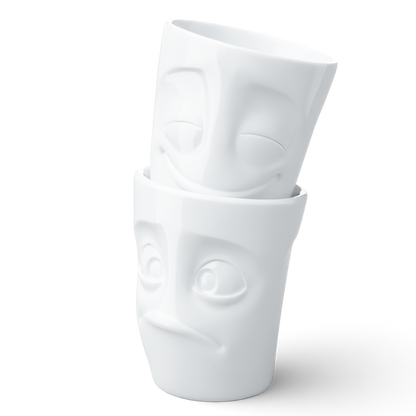 Set of two coffee mugs without handles in white from the porcelain product family of fun dishware by FIFTYEIGHT Products. Each offering 11 oz capacity. Dishwasher and microwave safe coffee cups with 'Cheery' and 'Baffled' facial expression. Shipped in exclusively designed gift box.