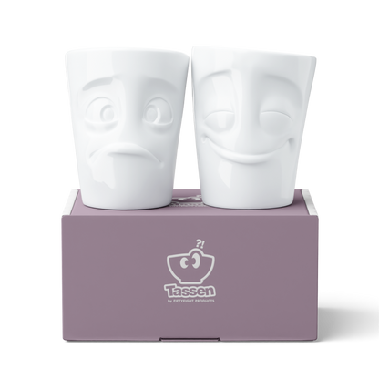 Set of two coffee mugs without handles in white from the porcelain product family of fun dishware by FIFTYEIGHT Products. Each offering 11 oz capacity. Dishwasher and microwave safe coffee cups with 'Cheery' and 'Baffled' facial expression. Shipped in exclusively designed gift box.