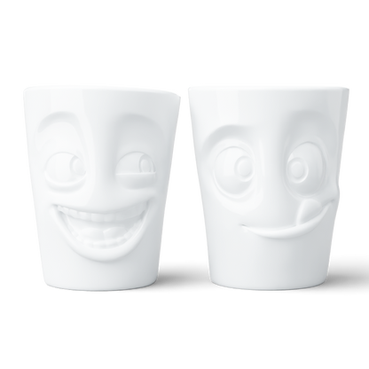 Set of two coffee mugs without handles in white from the porcelain product family of fun dishware by FIFTYEIGHT Products. Each offering 11 oz capacity. Dishwasher and microwave safe coffee cups with a 'joking' and one with a 'tasty' facial expression. Shipped in exclusively designed gift box.