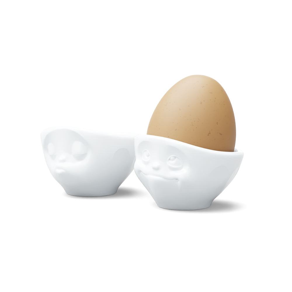 Set of two egg cups in white from the porcelain product family of fun dishware by FIFTYEIGHT Products. Set features two egg cups in white, featuring 'kissing' and 'dreamy' facial expressions. Dishwasher and microwave safe bowls. Shipped in exclusively designed gift box.