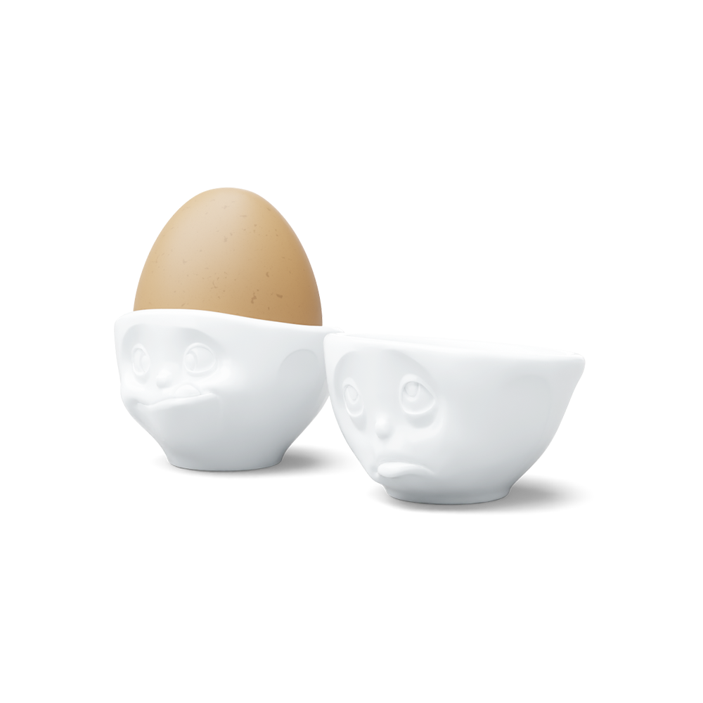 Set of two egg cups in white from the porcelain product family of fun dishware by FIFTYEIGHT Products. Set features two egg cups in white, featuring 'Oh please' and 'tasty' facial expressions. Dishwasher and microwave safe bowls. Shipped in exclusively designed gift box.