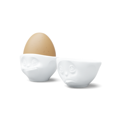 Set of two egg cups in white from the porcelain product family of fun dishware by FIFTYEIGHT Products. Set features two egg cups in white, featuring 'Oh please' and 'tasty' facial expressions. Dishwasher and microwave safe bowls. Shipped in exclusively designed gift box.