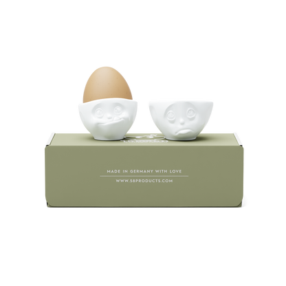 Set of two egg cups in white from the porcelain product family of fun dishware by FIFTYEIGHT Products. Set features two egg cups in white, featuring 'Oh please' and 'tasty' facial expressions. Dishwasher and microwave safe bowls. Shipped in exclusively designed gift box.