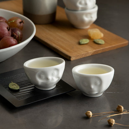 Set of two egg cups in white from the porcelain product family of fun dishware by FIFTYEIGHT Products. Set features two egg cups in white, featuring 'Oh please' and 'tasty' facial expressions. Dishwasher and microwave safe bowls. Shipped in exclusively designed gift box.
