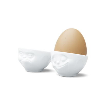 Set of two egg cups in white from the porcelain product family of fun dishware by FIFTYEIGHT Products. Set features two egg cups in white, featuring 'Happy' and 'Hmpff' facial expressions. Dishwasher and microwave safe bowls. Shipped in exclusively designed gift box.
